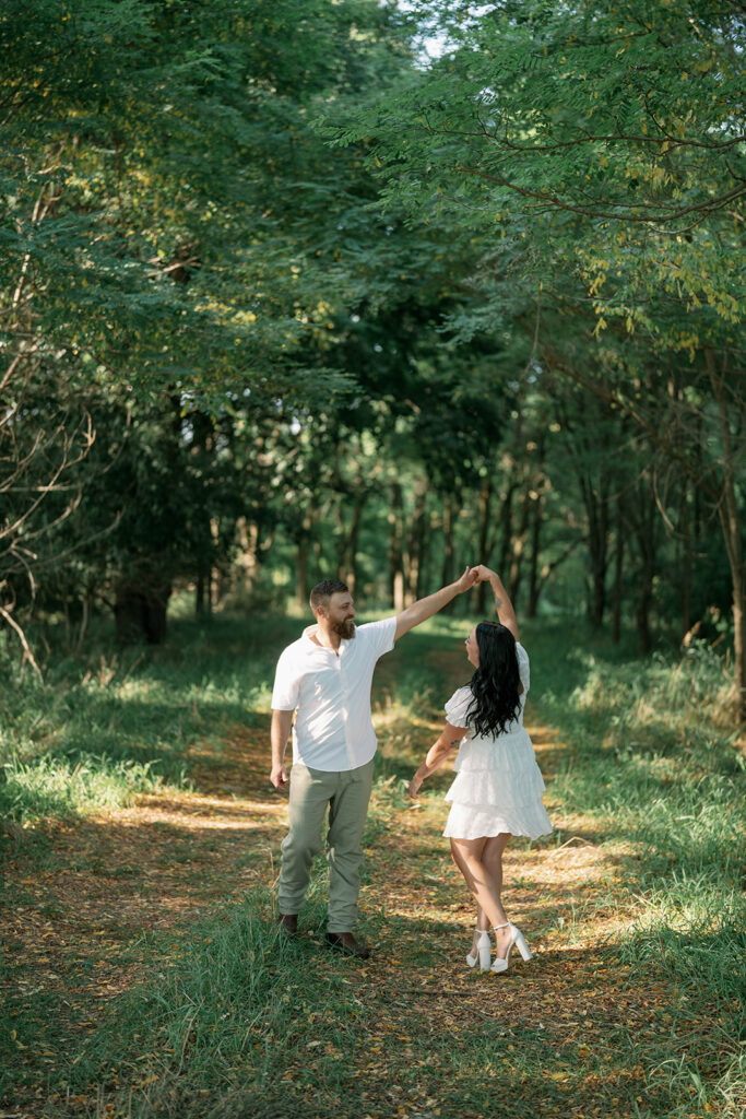 Engaged couple dancing together in the woods during their Michigan engagement session