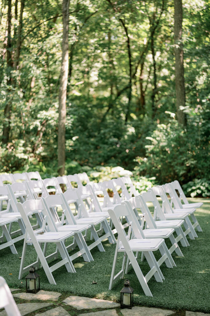 White ceremony chairs at Stonegate Manor surrounded by lush gardens near Lake Michigan