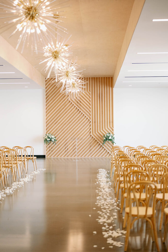 Couple standing inside Leona Road ceremony space with tall windows and contemporary wood feature wall