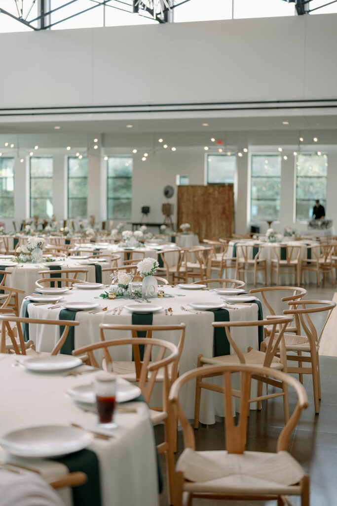 Reception tables at Leona Road set with greenery and modern place settings inside this Grand Rapids wedding venue