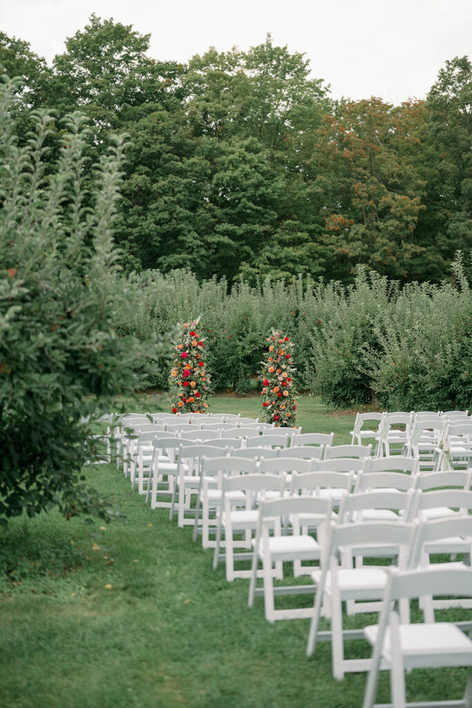 Outdoor ceremony setup at Nugent Orchards in Frankfort Michigan with orchard rows and summer greenery