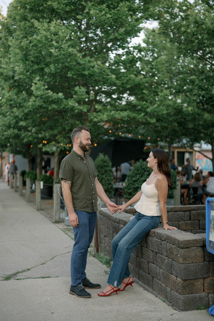 Couple laughing together outside Sawyer Market in Sawyer Michigan, small-town engagement session with candid moments.