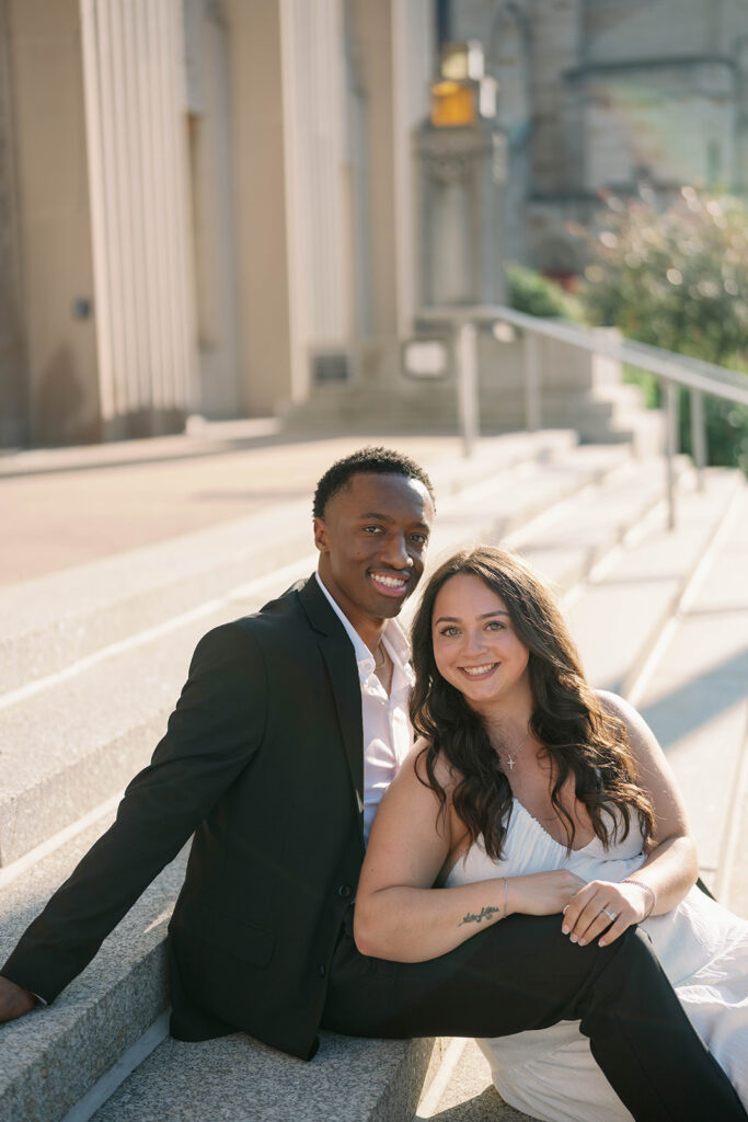 Romantic engagement photo of couple sitting on city steps in downtown Kalamazoo, natural candid pose