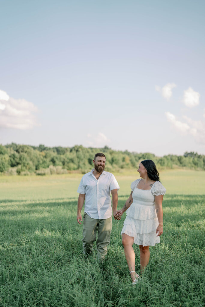 Couple walking through a green open field during their Michigan engagement session