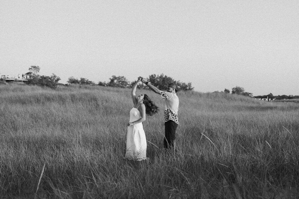 Couple dancing together in a field during their photography session with Raechel Marie Photo captured in black and white