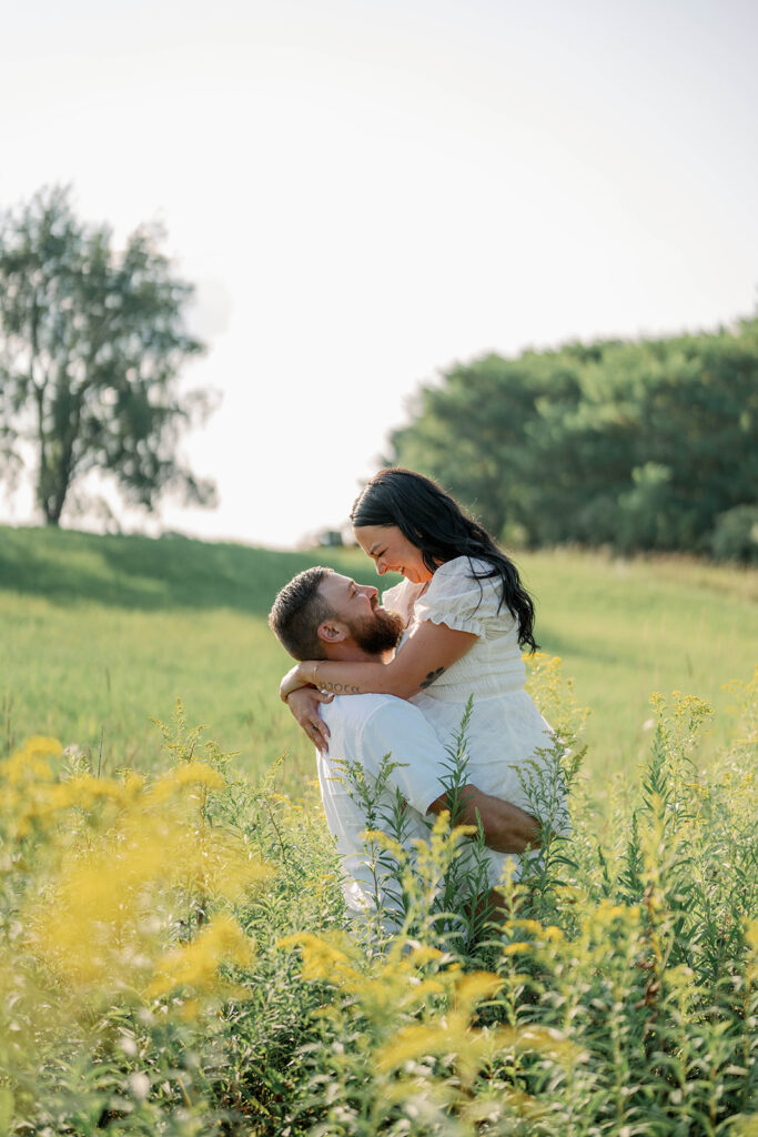 Couple playfully spinning in a field during their outdoor Michigan engagement session