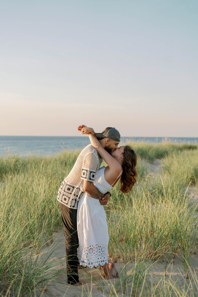 Couple holding their child while hugging in a tall grassy field during their family photography session