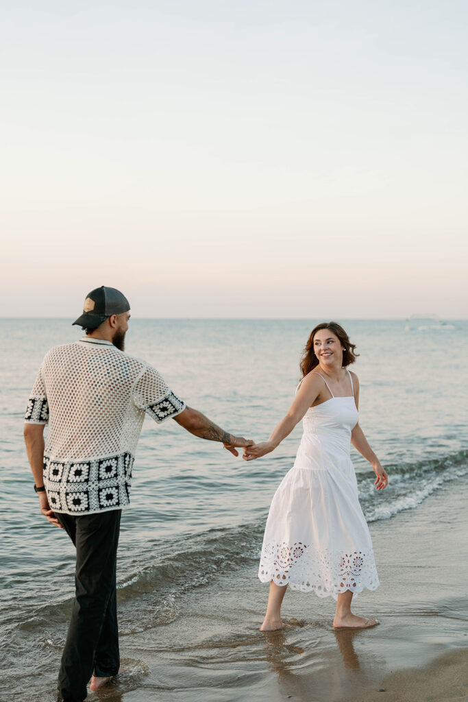 Couple holding hands and running along the shoreline during their beach photography session