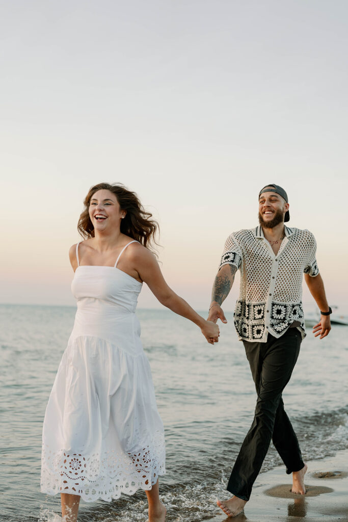 Couple laughing and walking in the water during their Lake Michigan photography session