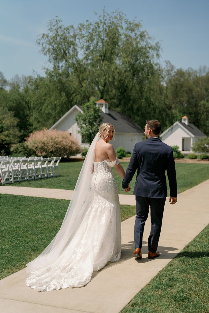 Couple walking the grounds at Baypointe Woods with white modern cottage style buildings and bright natural light