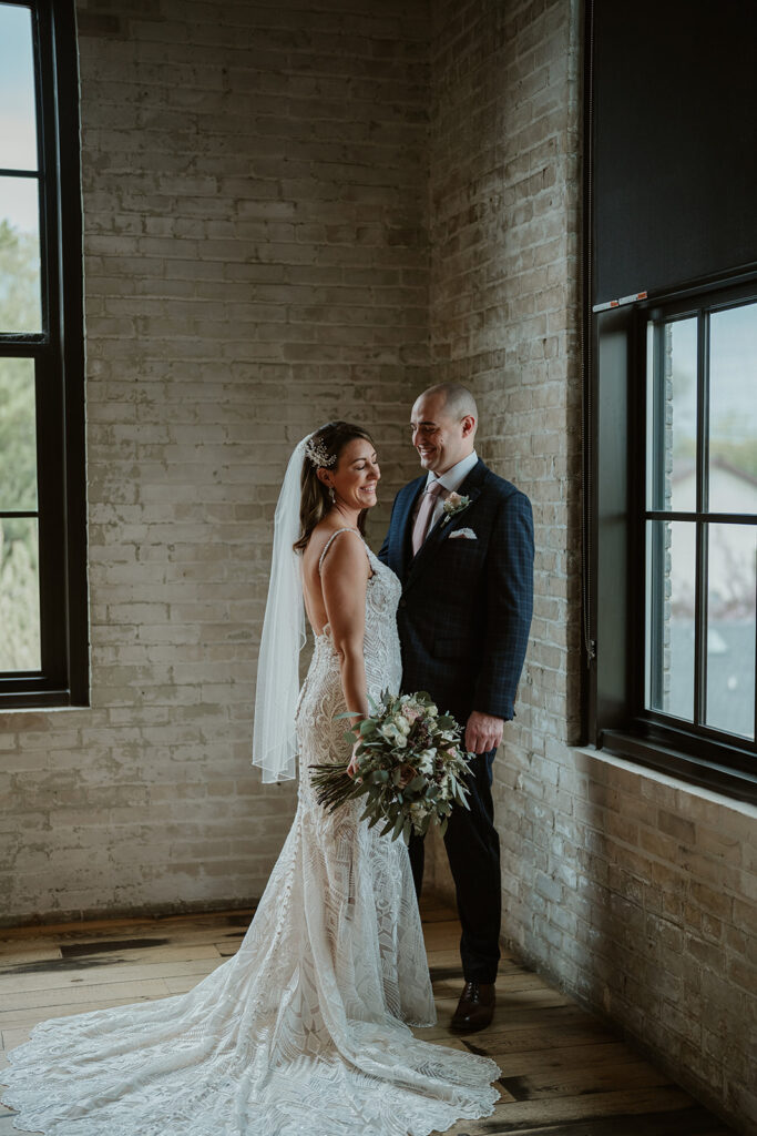 Bride and groom standing inside Journeyman Distillery surrounded by rustic wooden beams and natural light