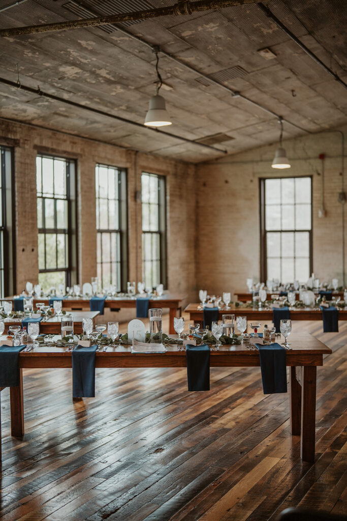 Wedding reception setup at Journeyman Distillery with long wooden tables and vintage industrial decor