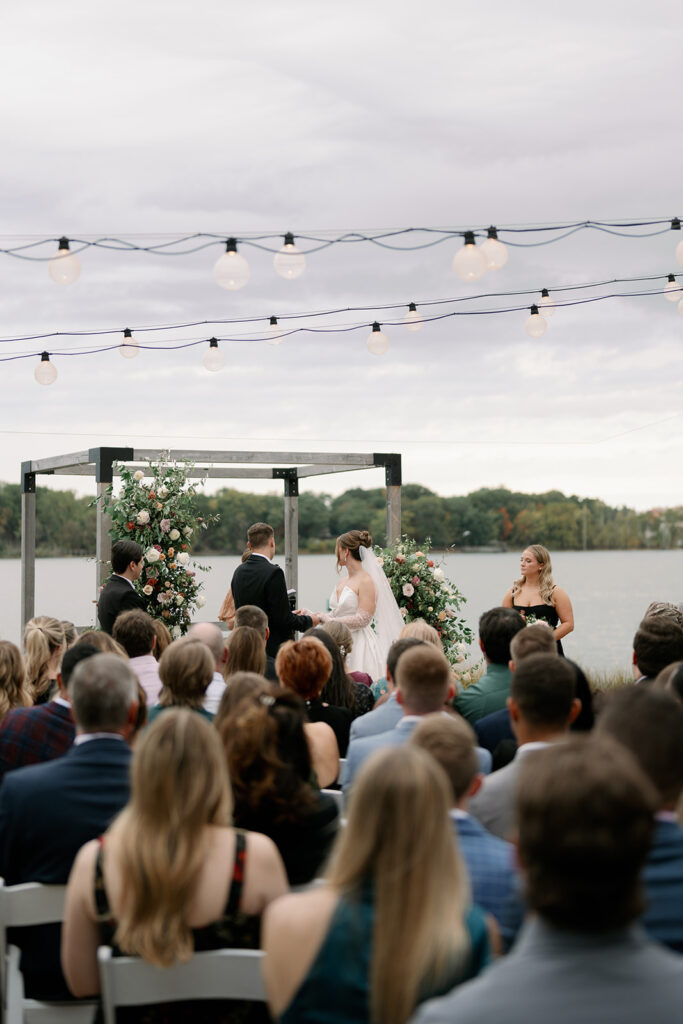 Outdoor wedding ceremony at Boatwerks in Holland with guests seated overlooking Lake Macatawa during a West Michigan wedding