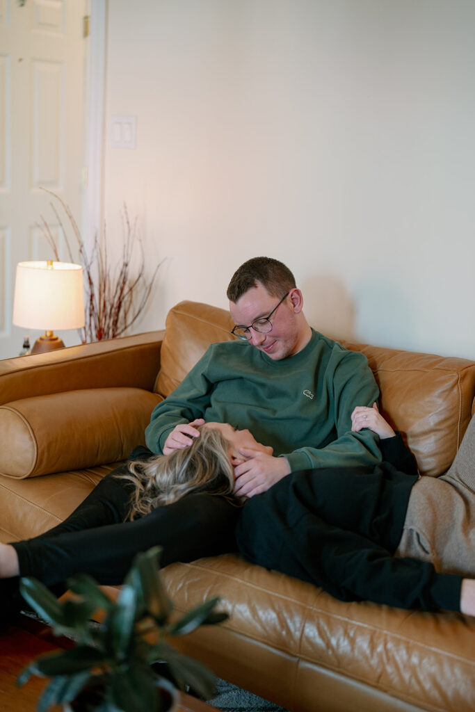 Engaged couple relaxing at home with their dog during cozy lifestyle engagement session.