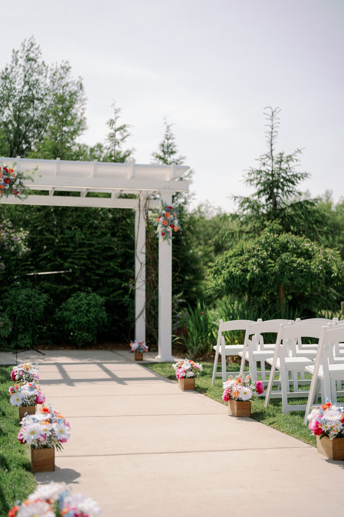 Outdoor ceremony arch at Baypointe Woods surrounded by tall trees and natural greenery
