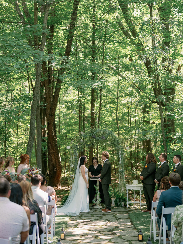 Outdoor ceremony under tall trees at Stonegate Manor in Benton Harbor during a romantic Michigan garden wedding