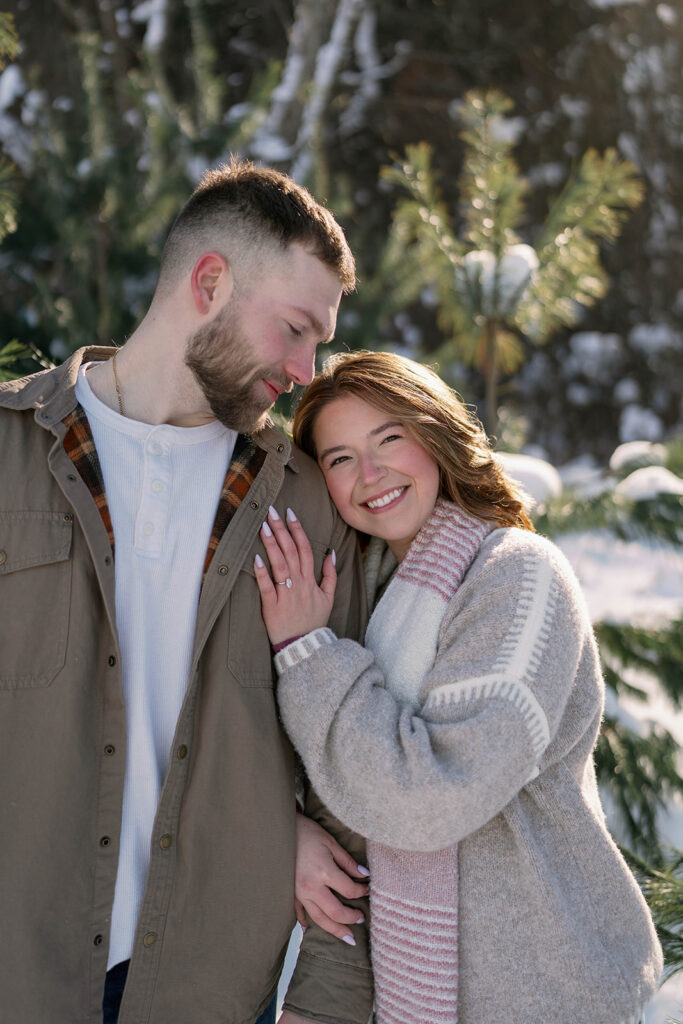 Warm winter portrait of a couple smiling together with snowy Michigan woods in the background