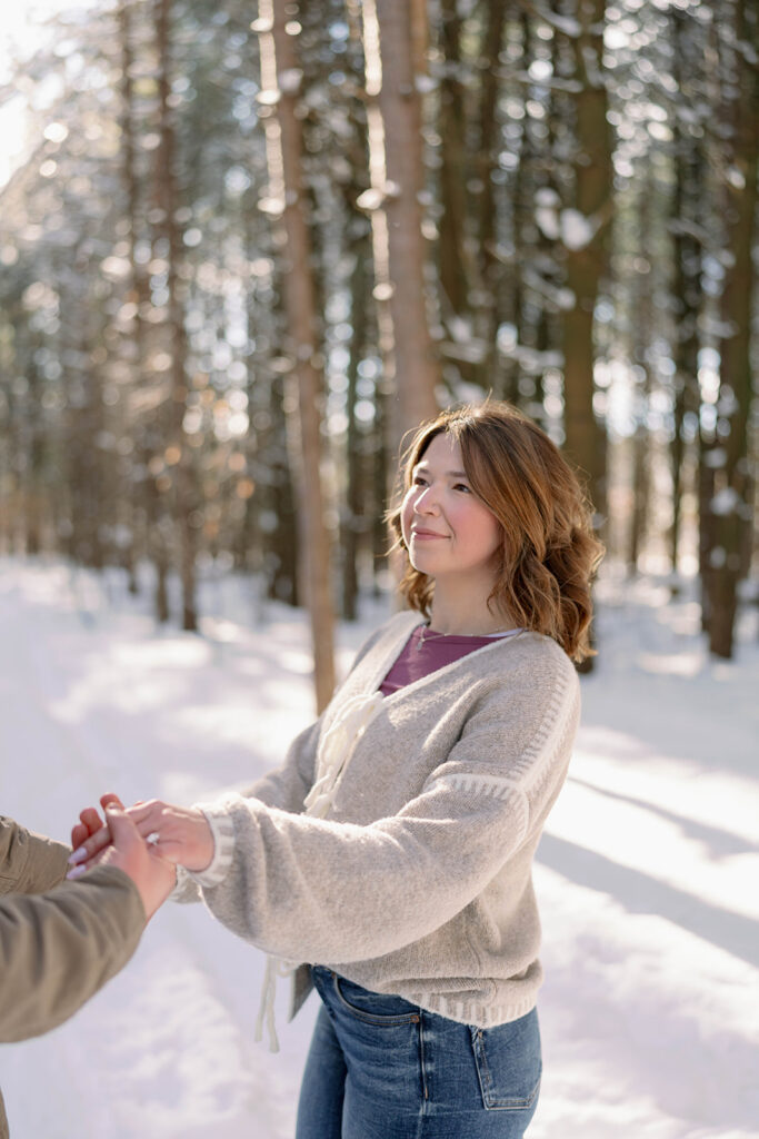 Woman holding hands with her partner during a winter photo session in Southwest Michigan woods