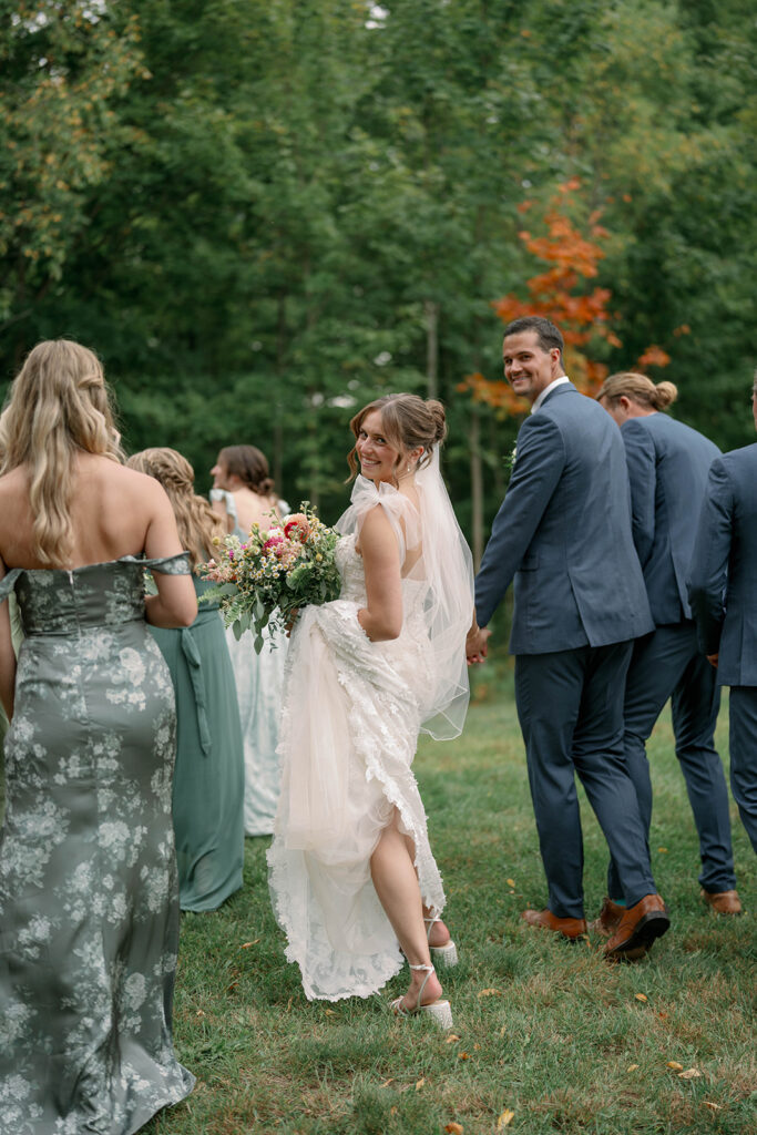 bride looking over shoulder while walking with bridal party at Nugent Orchards wedding