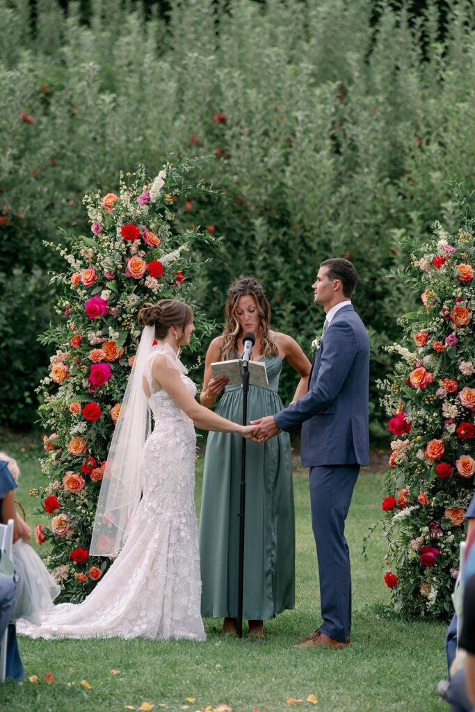 couple holding hands during ceremony at Nugent Orchards wedding in Michigan