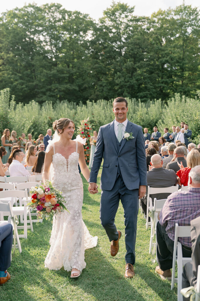 bride and groom exiting ceremony at Nugent Orchards wedding in Frankfort Michigan