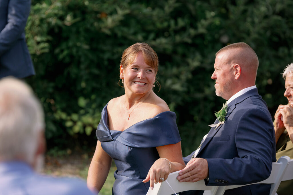 mother of bride smiling as bride walks down aisle at Nugent Orchards wedding