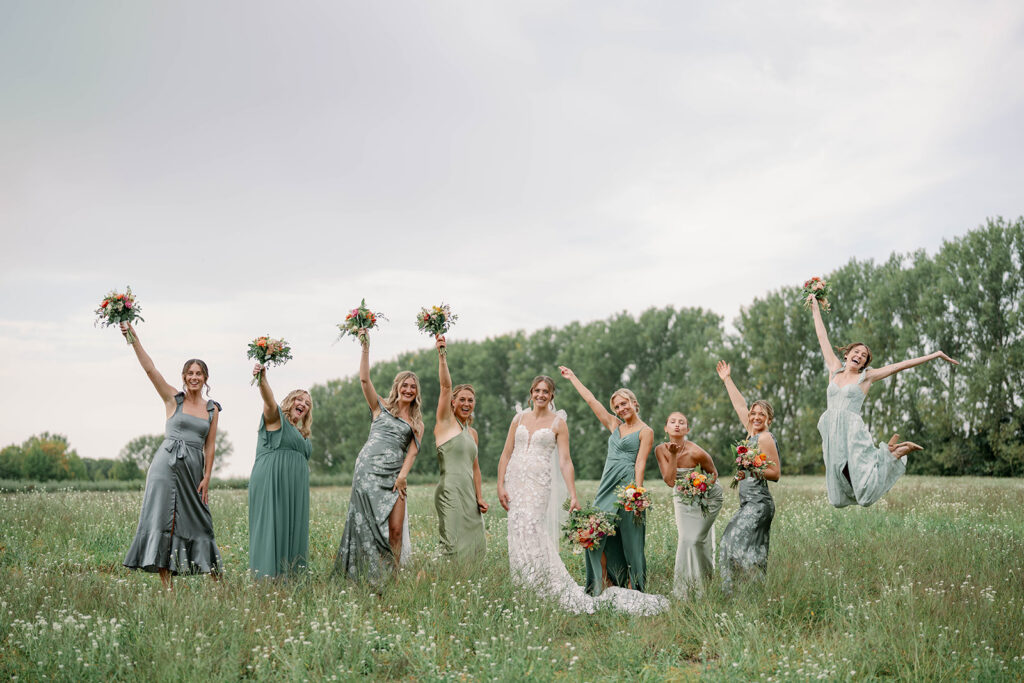 bride and bridesmaids celebrating in open field at Nugent Orchards wedding in Frankfort Michigan