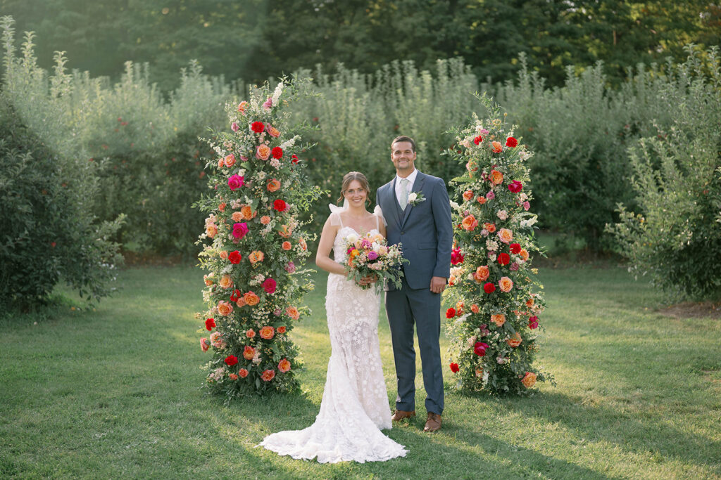 bride and groom posing in front of floral ceremony arches at Nugent Orchards wedding in Frankfort Michigan