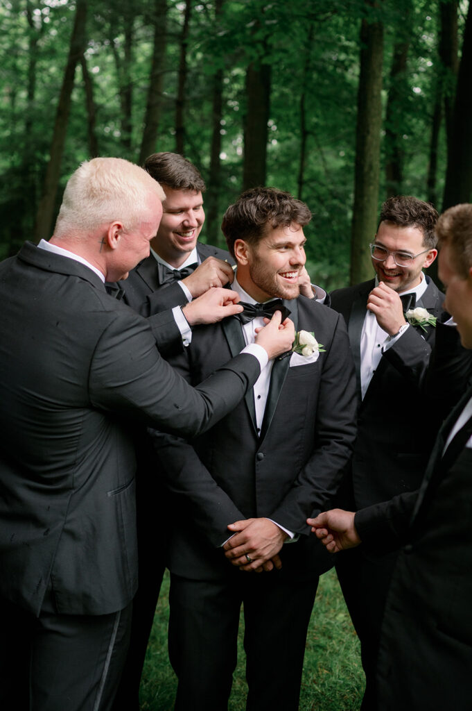 groomsmen helping groom with boutonniere wedding day Michigan