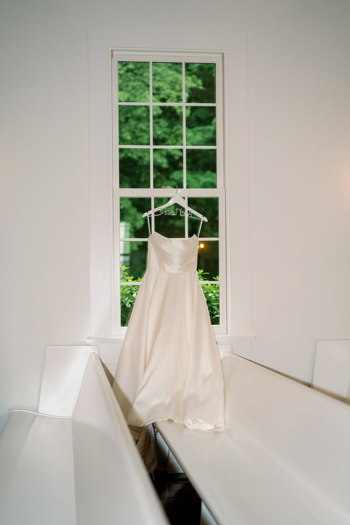 bridal gown hanging in window natural light Michigan wedding