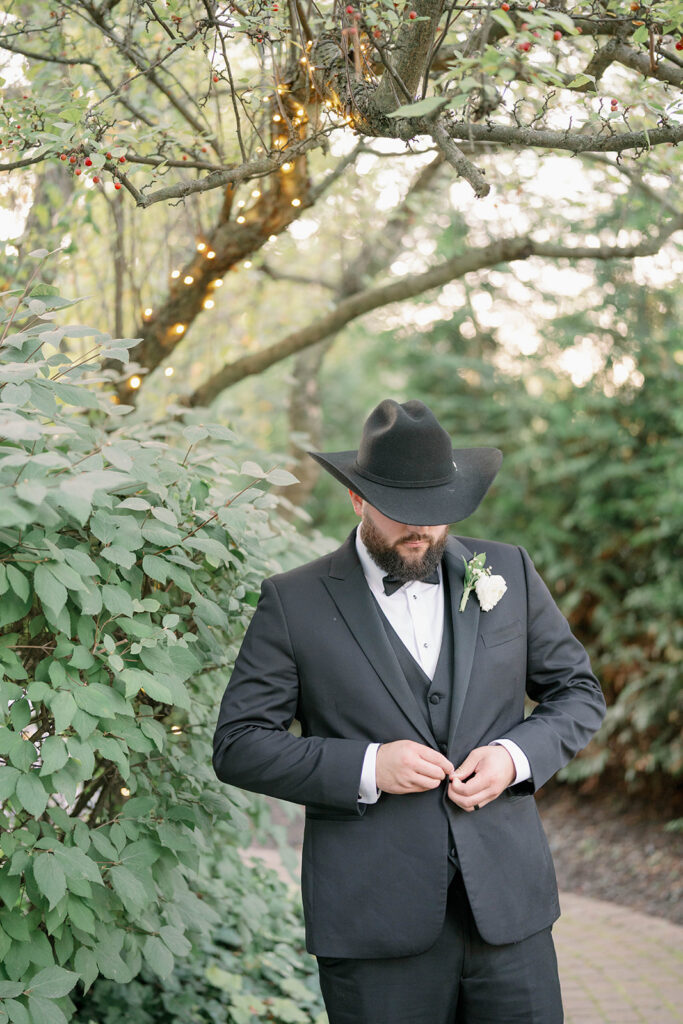 groom adjusting jacket in garden during Cafe Cortina wedding in Dearborn Michigan