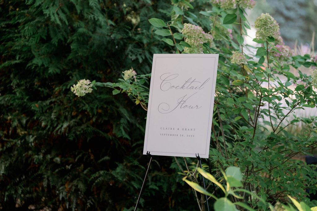 cocktail hour sign surrounded by greenery at Cafe Cortina wedding in Dearborn Michigan